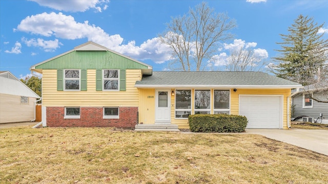 split level home featuring a front yard, concrete driveway, brick siding, and an attached garage