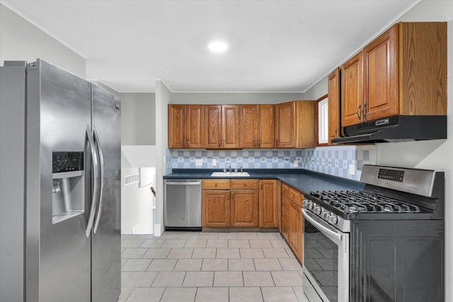 kitchen with stainless steel appliances, brown cabinetry, a sink, and under cabinet range hood