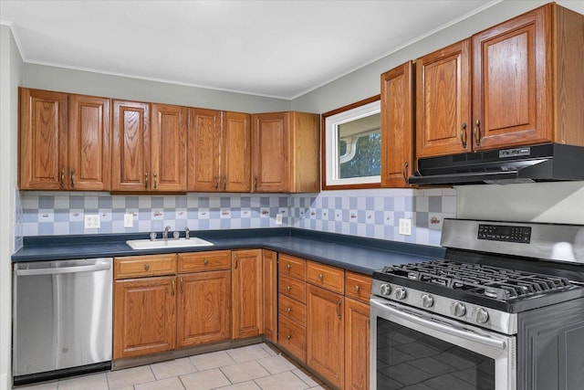 kitchen with brown cabinets, dark countertops, appliances with stainless steel finishes, a sink, and under cabinet range hood