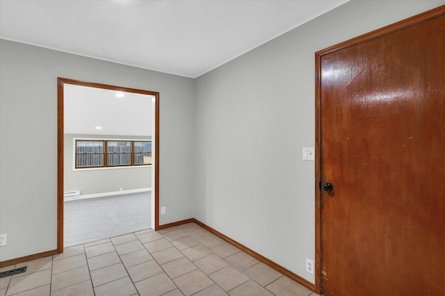 spare room featuring a baseboard radiator, visible vents, baseboards, and light tile patterned floors