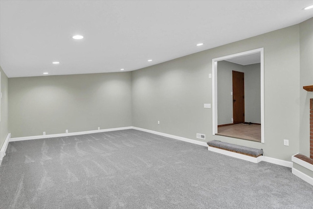 carpeted spare room featuring baseboards, a fireplace, visible vents, and recessed lighting