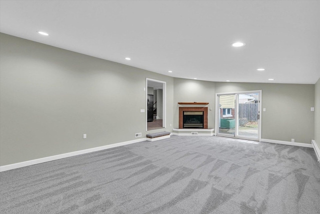 unfurnished living room with carpet floors, recessed lighting, a brick fireplace, and baseboards