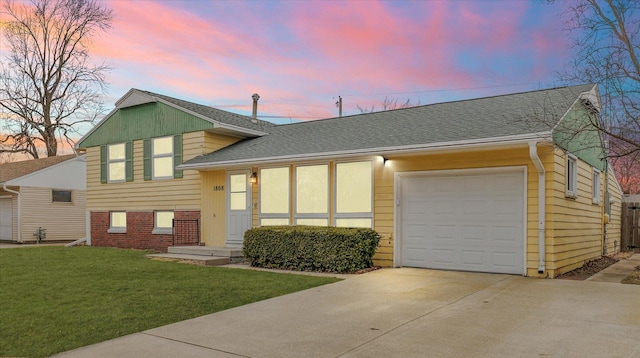 tri-level home featuring a garage, a shingled roof, brick siding, concrete driveway, and a front lawn