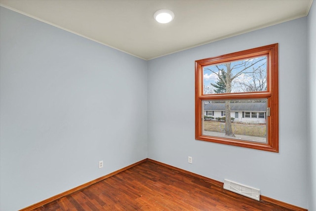 unfurnished room featuring baseboards, visible vents, and dark wood-style flooring