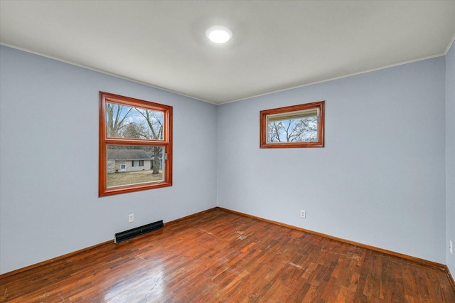 empty room featuring baseboards, visible vents, and hardwood / wood-style floors