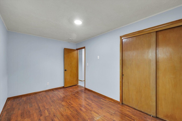 unfurnished bedroom featuring a closet, wood finished floors, and baseboards