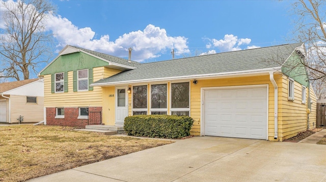 tri-level home with brick siding, concrete driveway, roof with shingles, an attached garage, and a front yard