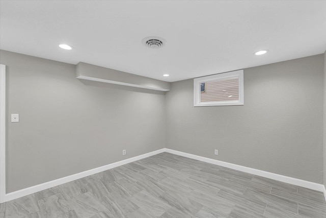 finished basement with light wood-style floors, recessed lighting, visible vents, and baseboards