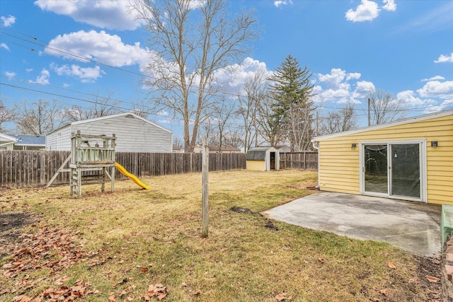 view of yard featuring a playground, a patio, an outdoor structure, and a fenced backyard