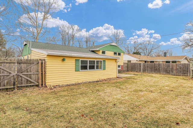 rear view of property featuring a fenced backyard, a gate, and a yard