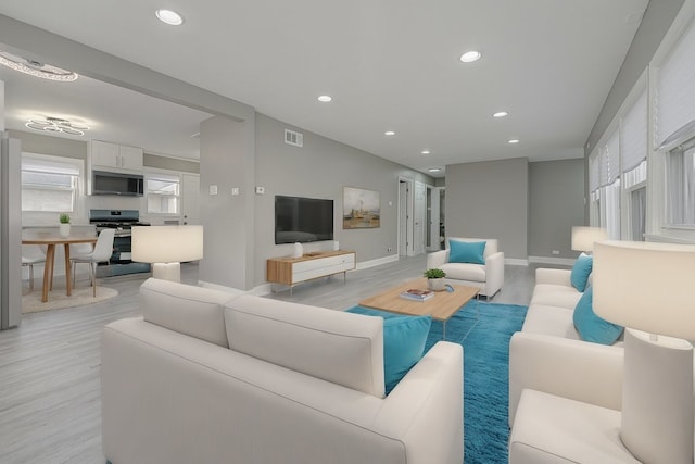 living room featuring baseboards, light wood-type flooring, visible vents, and recessed lighting