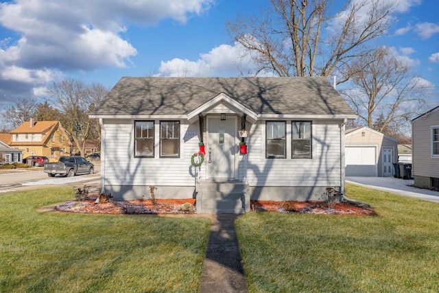 bungalow-style home with concrete driveway, a detached garage, roof with shingles, an outdoor structure, and a front lawn