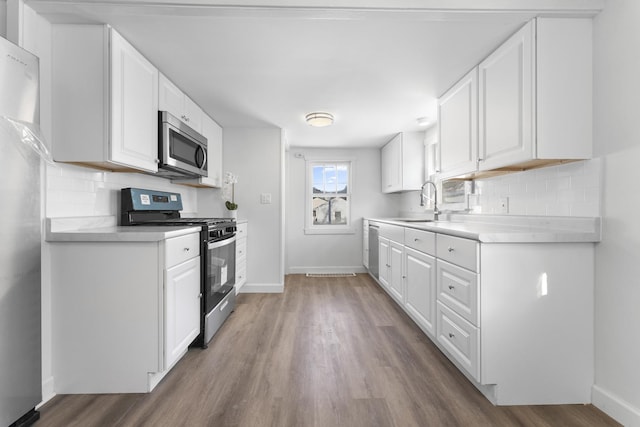 kitchen with light countertops, appliances with stainless steel finishes, a sink, and tasteful backsplash