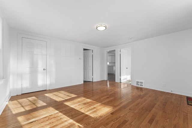 unfurnished bedroom with wood finished floors, visible vents, and baseboards