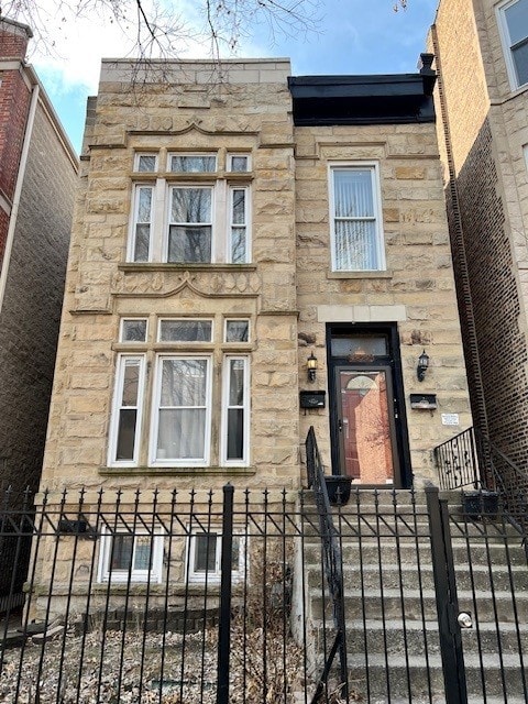 view of front of house with a fenced front yard and stone siding
