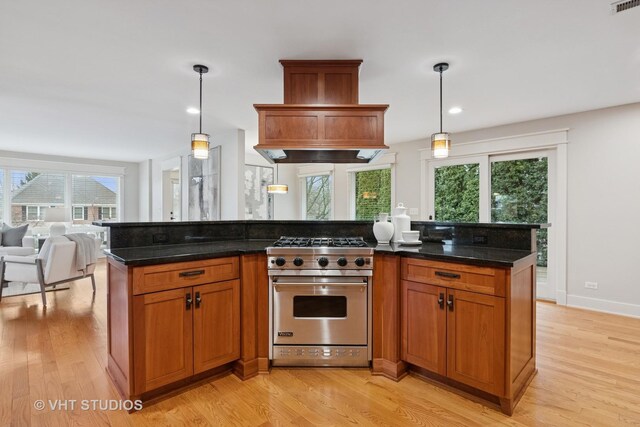 kitchen with open floor plan, light wood finished floors, premium stove, and brown cabinets