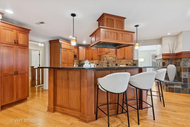 living room featuring recessed lighting, visible vents, a tiled fireplace, wood finished floors, and baseboards