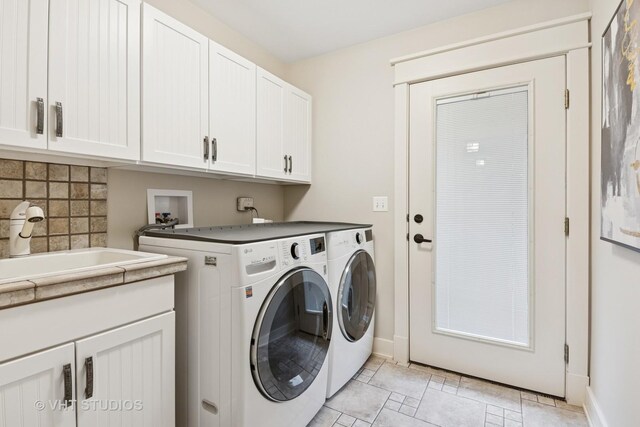 laundry area with baseboards, a sink, cabinet space, and washer and dryer