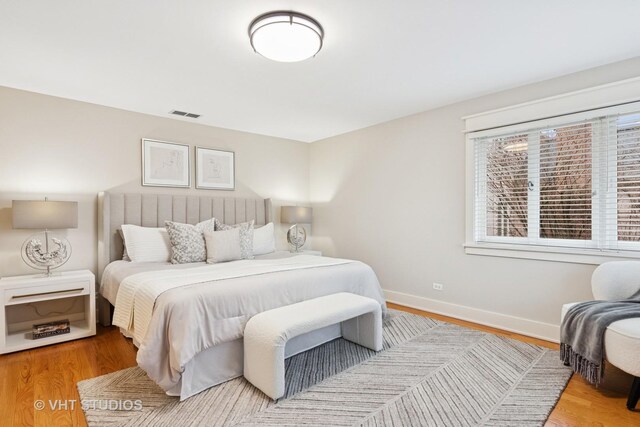 bedroom with wood finished floors, visible vents, and baseboards