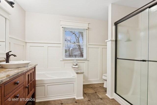 full bathroom featuring toilet, a stall shower, a decorative wall, and a bath