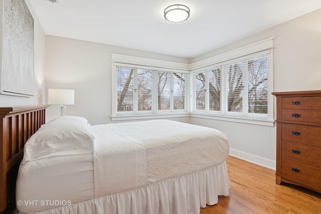 bedroom featuring baseboards, multiple windows, and light wood finished floors