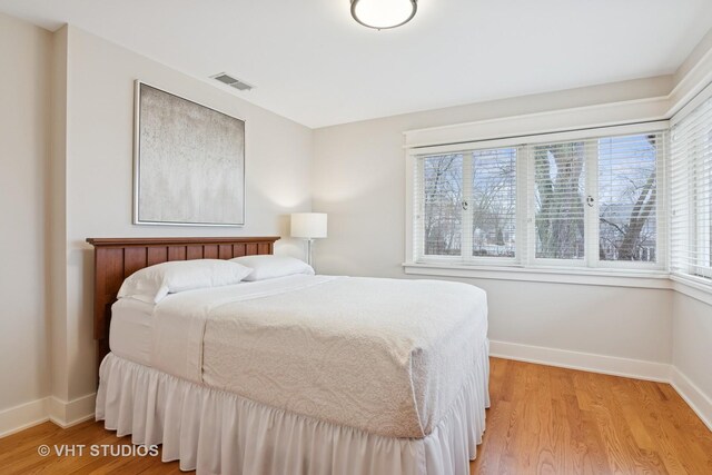 bedroom featuring baseboards, multiple windows, and light wood finished floors