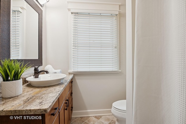 bathroom with baseboards, vanity, and toilet