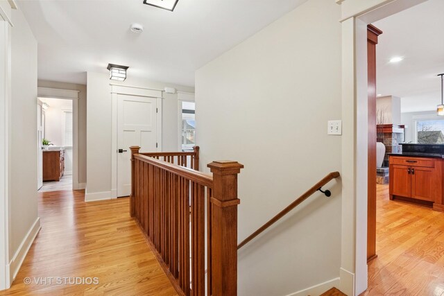 hallway with light wood-type flooring, baseboards, an upstairs landing, and recessed lighting