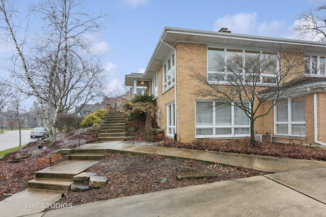 view of home's exterior with stairs and brick siding