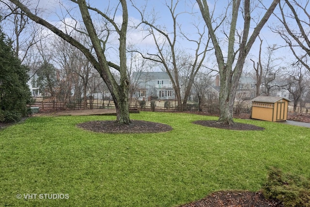 view of yard with a shed, fence, and an outbuilding