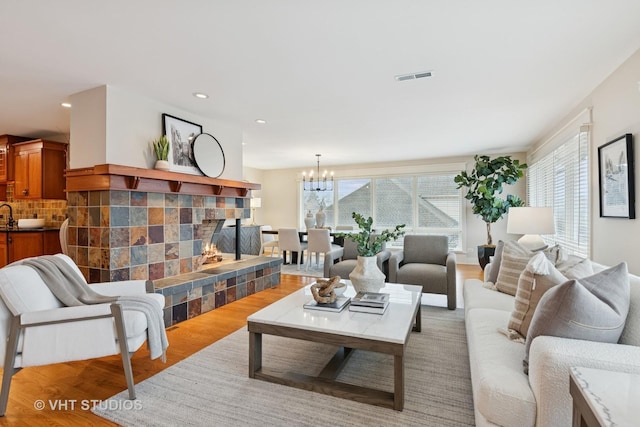 living area featuring recessed lighting, a fireplace, visible vents, light wood-type flooring, and an inviting chandelier