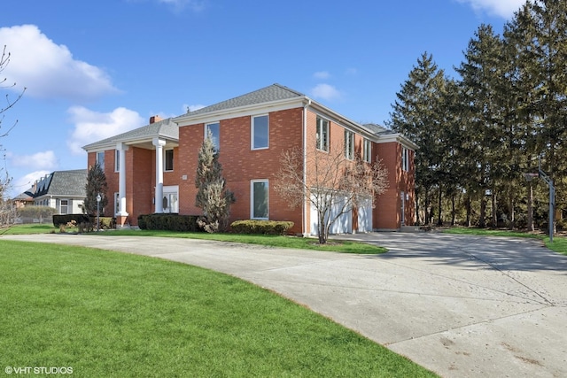 exterior space featuring concrete driveway, brick siding, an attached garage, and a front yard