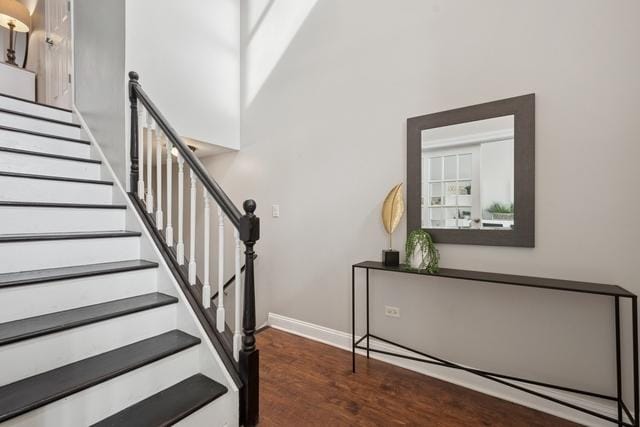 stairway with a towering ceiling, baseboards, and wood finished floors