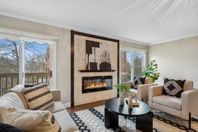 living room with baseboards, a fireplace, ornamental molding, and wood finished floors