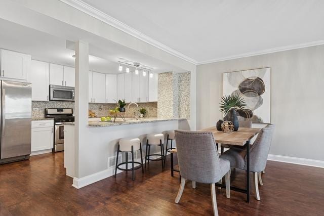 dining room with baseboards, dark wood finished floors, and crown molding