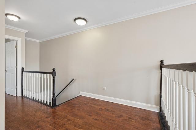 empty room with baseboards, wood finished floors, and crown molding