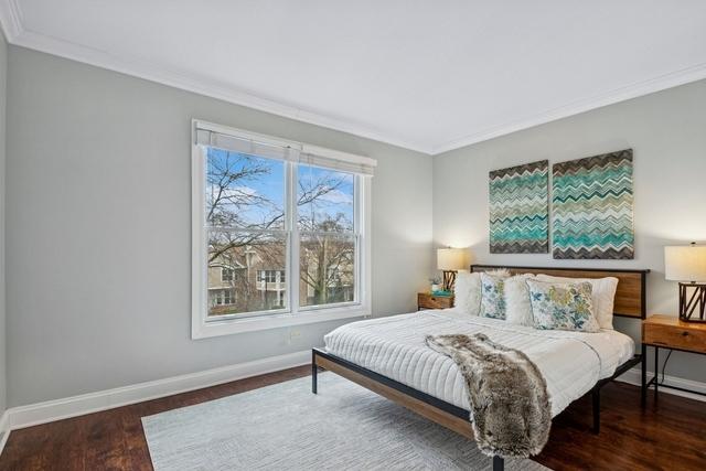 bedroom with crown molding, wood finished floors, and baseboards