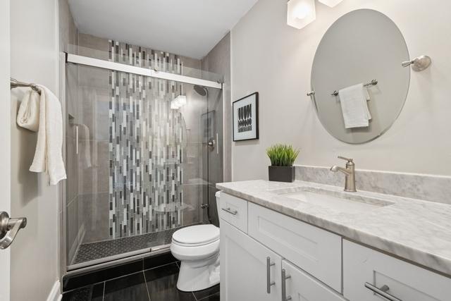 bathroom featuring a stall shower, vanity, and toilet