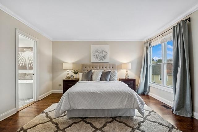 bedroom featuring baseboards, visible vents, ornamental molding, and wood finished floors