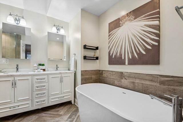 full bath featuring a freestanding bath, double vanity, and a sink