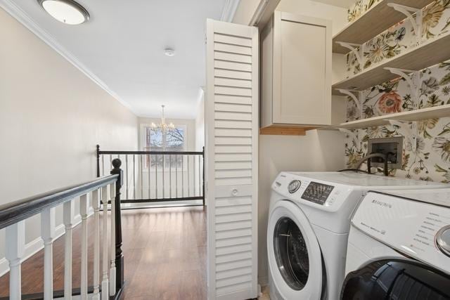 laundry area with washing machine and clothes dryer, cabinet space, ornamental molding, wood finished floors, and a chandelier