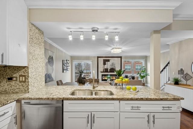 kitchen featuring crown molding, white cabinets, a sink, and stainless steel dishwasher