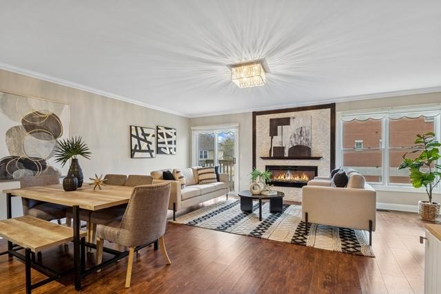 dining area with baseboards, ornamental molding, wood finished floors, and a glass covered fireplace