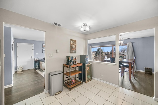 interior space featuring light tile patterned floors, baseboards, visible vents, and a notable chandelier