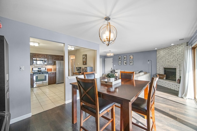 dining area with a brick fireplace, baseboards, and wood finished floors