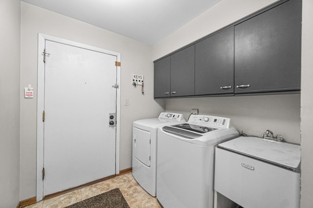 clothes washing area featuring cabinet space, a sink, washer and clothes dryer, and baseboards