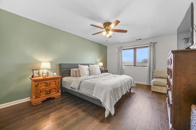 bedroom featuring visible vents, baseboards, dark wood finished floors, and a ceiling fan