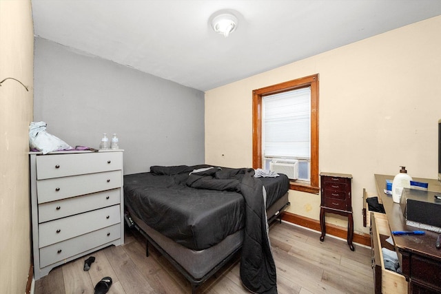 bedroom featuring light wood-style floors, cooling unit, and baseboards