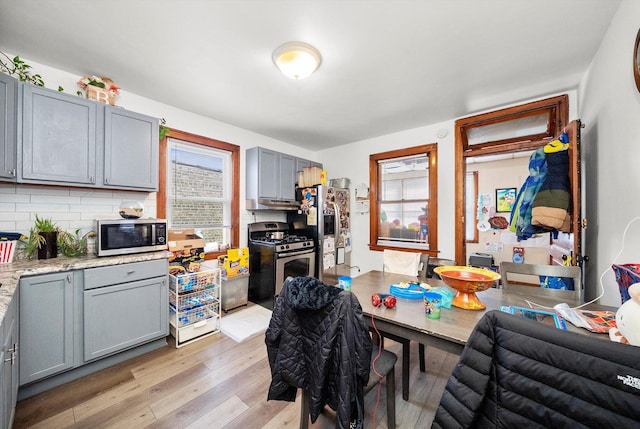 kitchen with appliances with stainless steel finishes, decorative backsplash, gray cabinets, and light wood-style floors