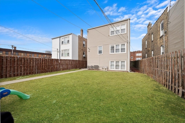 rear view of house with a fenced backyard and a yard